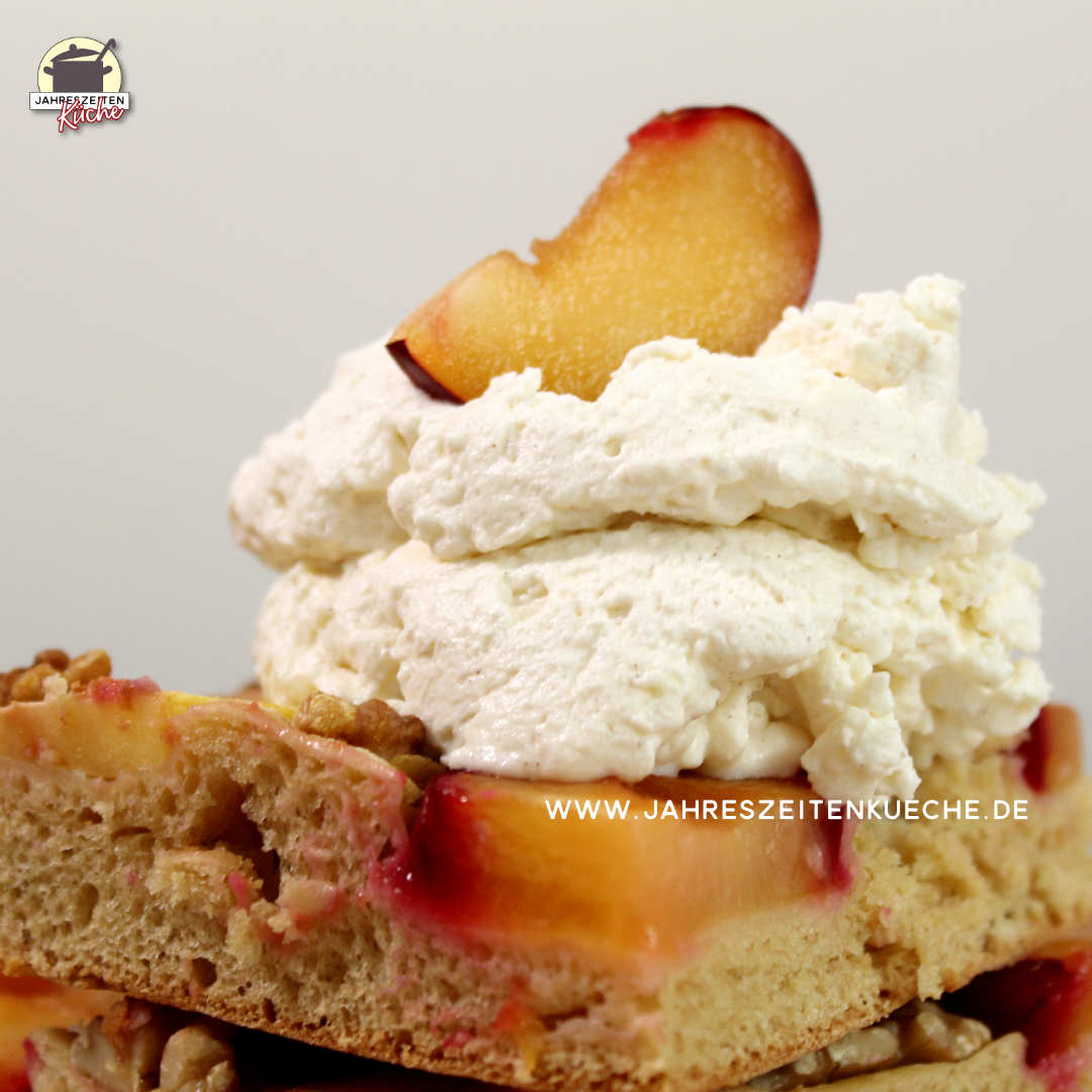 Ein Stück Apfel-Pflaumen-Kuchen mit Schlagsahne. Darauf liegt eine Pflaumensscheibe