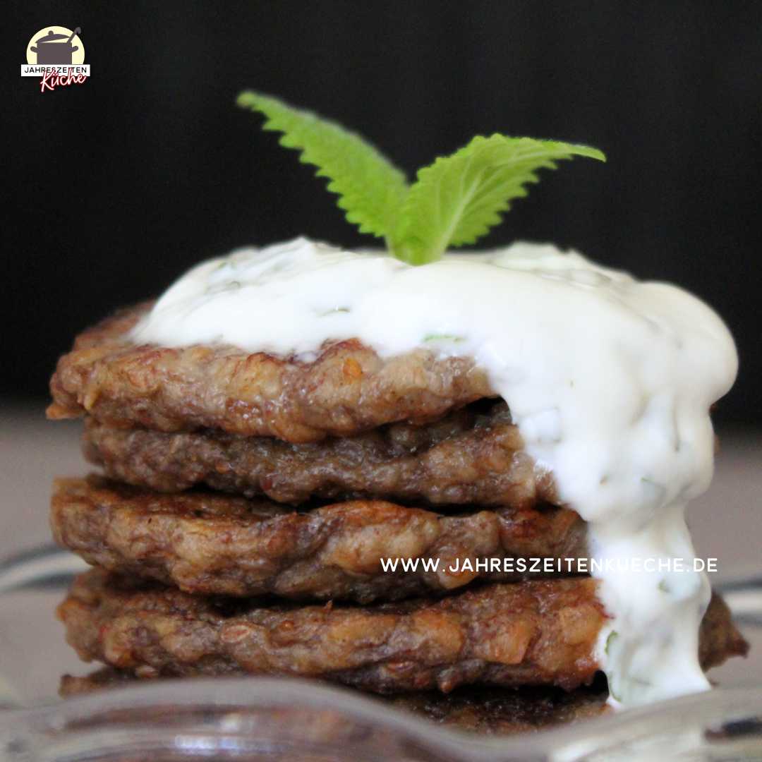 Zwei Blätter der Zitronenmelisse krönen einen Stapel Bananentaler. Joghurtsauce läuft darüber.