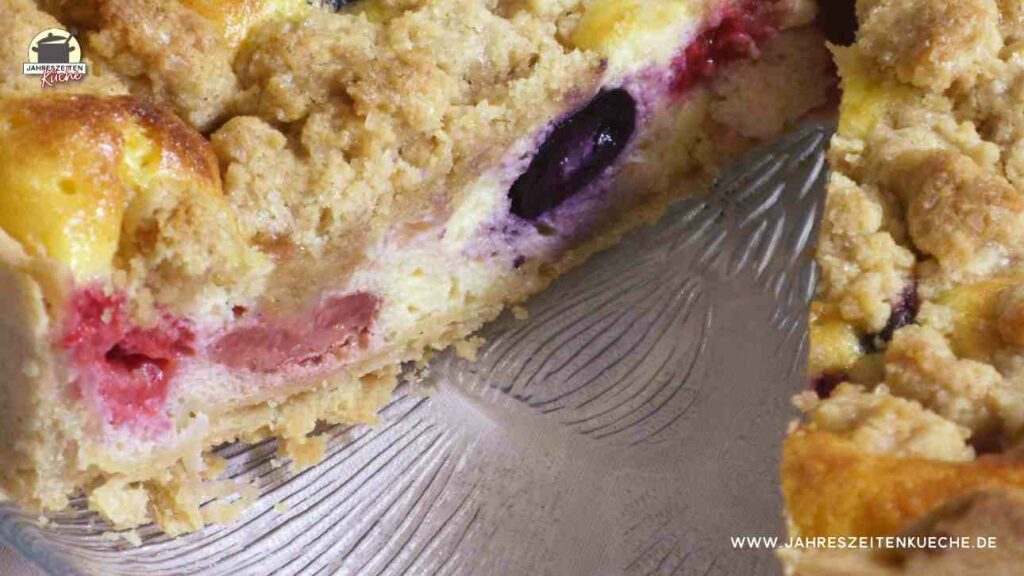 Käsekuchen mit Beeren und Streusel, von dem ein Stück fehlt