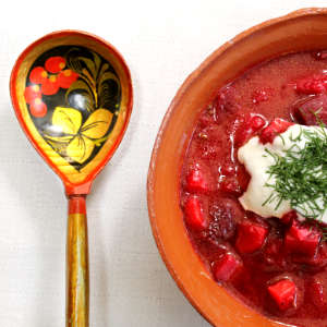 Eine irdene Tonschale mit Borschtsch. Daneben liegt ein russicher Löffel.