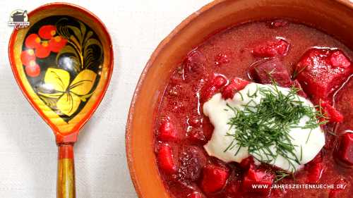 Eine irdene Tonschale mit Borschtsch. Daneben liegt ein russicher Löffel.