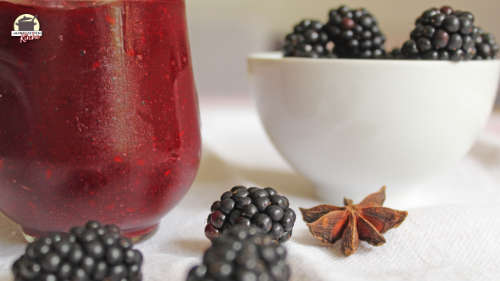 Ein Schälchen Brombeeren steht im Hintergrund. Davor liegen frische Brombeeren und Sternanis.