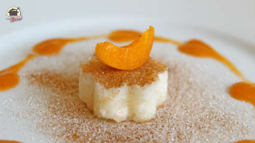 Buttermilchreis in Form einer kleinen Blume mit Zimt-Zucker bestreut. Darauf liegt eine Aprikosenspalte.