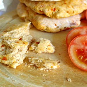 Auf einem Holzbrett liegen ein Stück Tomaten-Ciabatta und frische Tomaten.