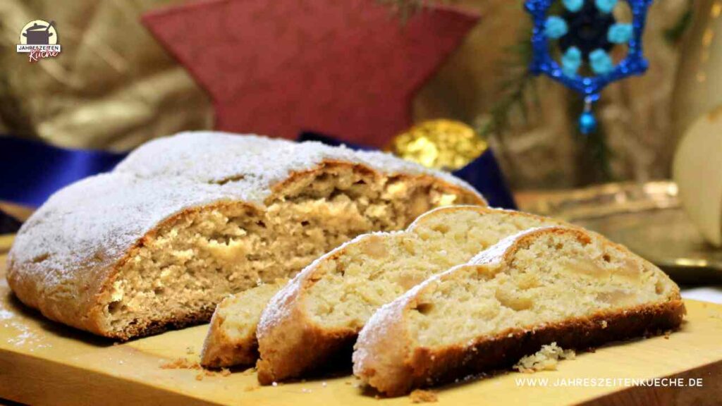 Auf einem Holzbrett liegt ein angeschnittener Mandel-Marzipan-Stollen.