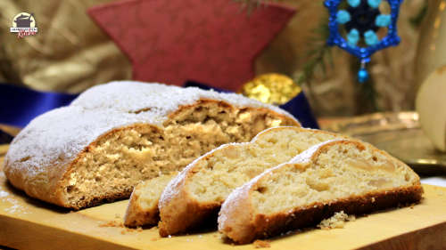 Auf einem Holzbrett liegt ein angeschnittener Mandel-Marzipan-Stollen.