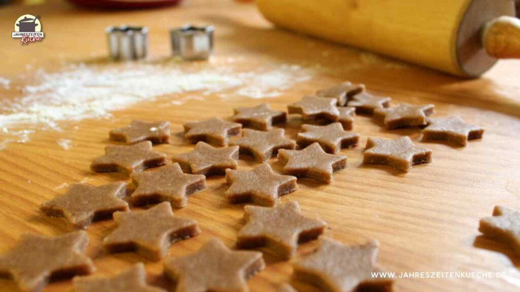 Nervenkekse sind zu Sternen ausgestochen. Im Hintergrund liegt eine Teigrolle