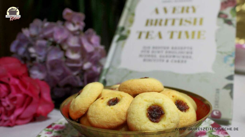 Vor dem Backbuch A Very British Teatime steht eine Schale mit englischen Marmeladen-Keksen. Daneben liegen eine Rose und eine Hortensie.