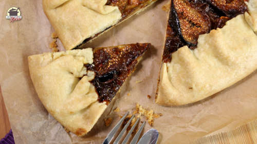 Aus einer Galette mit Feigen ist ein Stück herausgeschnitten. Daneben liegen Messer und Gabel.