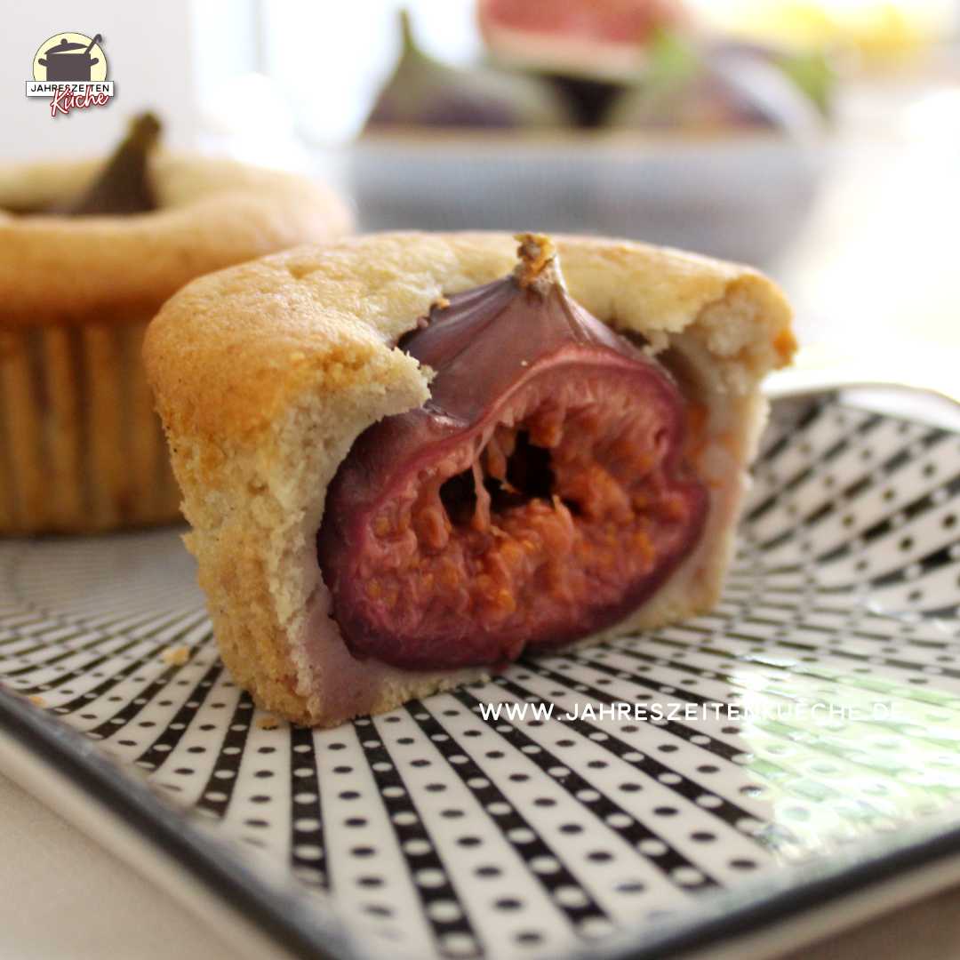 Auf einem Porzellantablett stehen zwei Feigen-Muffins. Das vordere ist aufgeschnitten