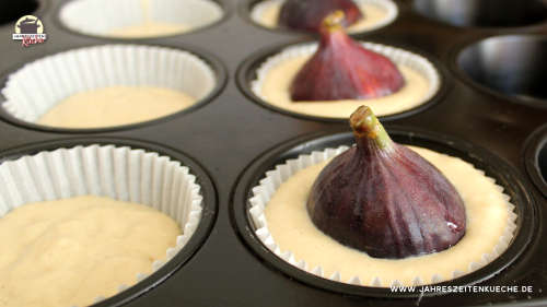 Muffinförmchen mit Teig, in dem frische Feigen stecken