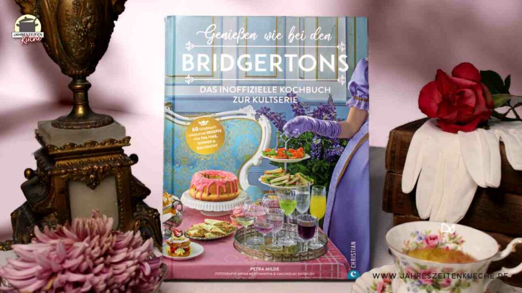 Links neben Petra Mildes Buch Genießen wie bei den Bridgertons steht ein alter kerzenleuchter, rechts daneben liegt eine Stapel mit alten Büchern.