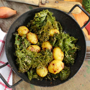 Eine emaillierte Pfanne mit Sesamkartoffeln und Grünkohl