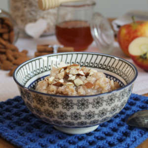 Ein Schälchen mit Habermus. Im Hintergrund steht ein Glas Honig.