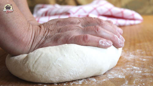 Hände kneten Teig auf einem Holztisch