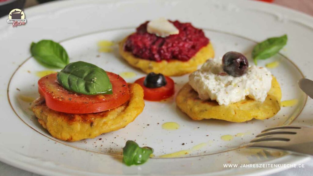 Drei Hüttenkäse-Puffer mit verschiedenen Toppings. Einmal mit Tomate und Basilikum, einmal mit Rote Bete-Aufstrich und einmal mit Schafskäsecreme und schwarzer Olive.
