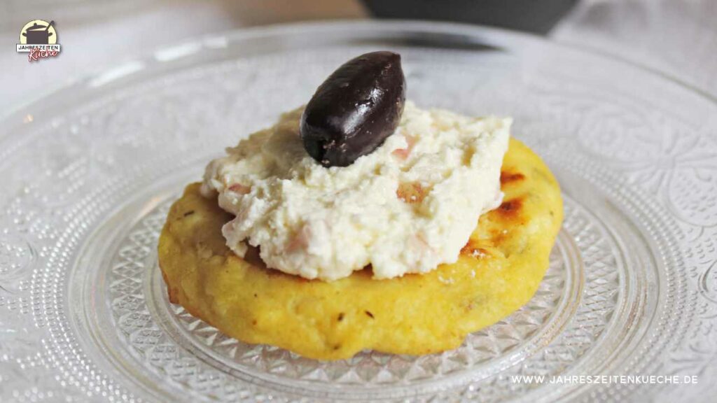 Hüttenkäse-Puffer mit Schafskäsecreme und einer schwarzen Olive.
