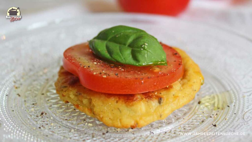Hüttenkäsepuffer mit einer Tomatenscheibe und einem Basilikumblatt darauf.