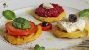 Drei Hüttenkäse-Puffer mit verschiedenen Toppings: Tomate-Basilikum, Rote Bete-Aufstrich, Schafskäsecreme-Olive.