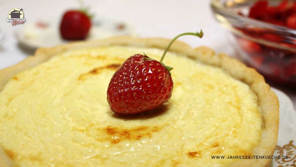 Auf einem Käsekuchen liegt eine frische Erdbeere