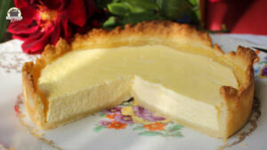 Ein angeschnittener Käsekuchen auf einem alten Teller mit Blumenmuster.