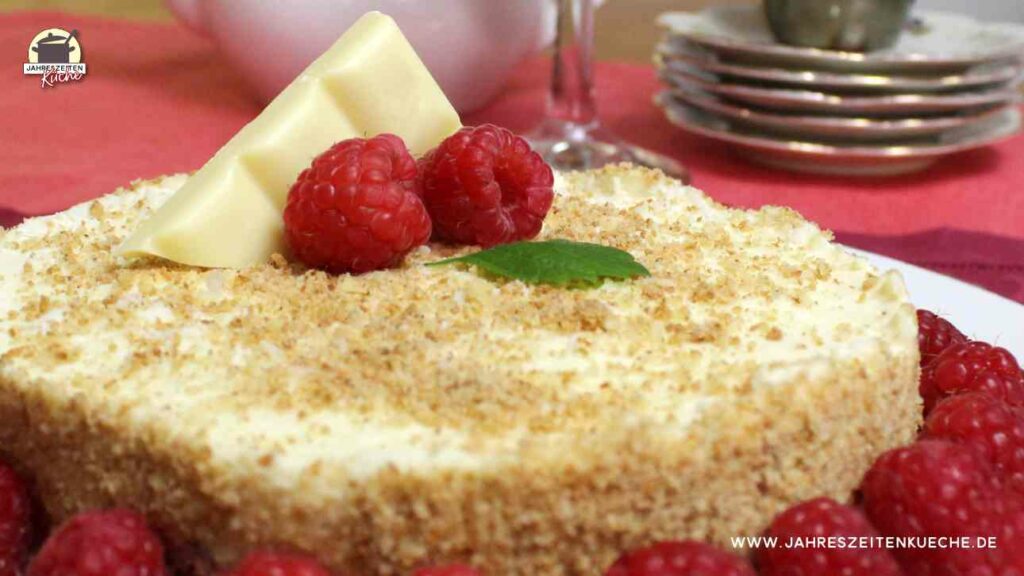 2 Himbeeren und ein Stück weiße Schokolade liegen auf einem No-Bake-Käsekuchen.