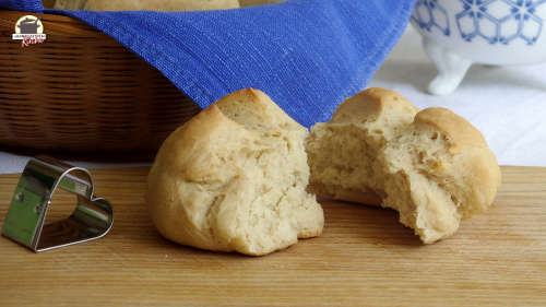 Vor einem Frühstückskorb liegt ein Holzbrett mit einem zerbrochenen Sonntagsbrötchen