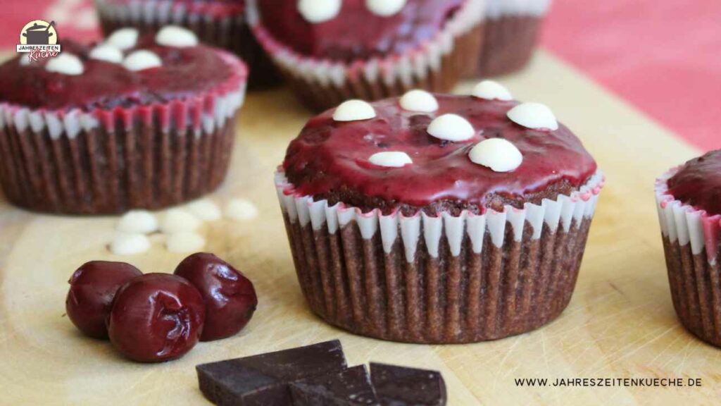 Schoko-Kirsch-Muffins, die wie Fliegenpilze aussehen auf einem Holzbrett