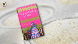 Buchcover "Kuchen backen in Kigali" im Vordergrund, im Hintergrund ein Muffinblech mit Muffins