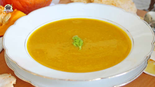 Ein weißer Teller mit Kürbis-Fenchelsuppe. Im Hintergrund liegt ein Hokkaidokürbis.