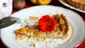 Auf einem Stück Kürbis-Quitten-Quiche liegt eine Blüte der Kapuzinerkresse