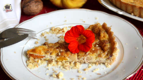 Auf einem Stück Kürbis-Quitten-Quiche liegt eine Blüte der Kapuzinerkresse