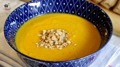 Kürbis-Bananensuppe mit gehackten Erdnüsse bestreut ist in einer blauen Schale mit weißem Muster