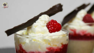 Groß im Vordergrund steht ein Glas mit Mandelcreme und Himbeermus. Im Hintergrund sind weitere unscharf zu sehen.
