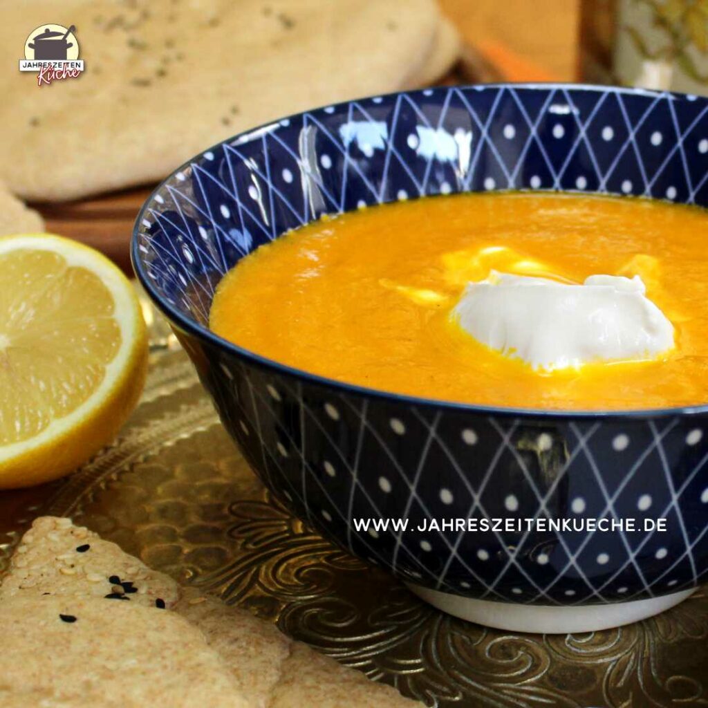 Marokkanische Karottensuppe steht auf einem Messingtablett neben einer halben Zitrone.