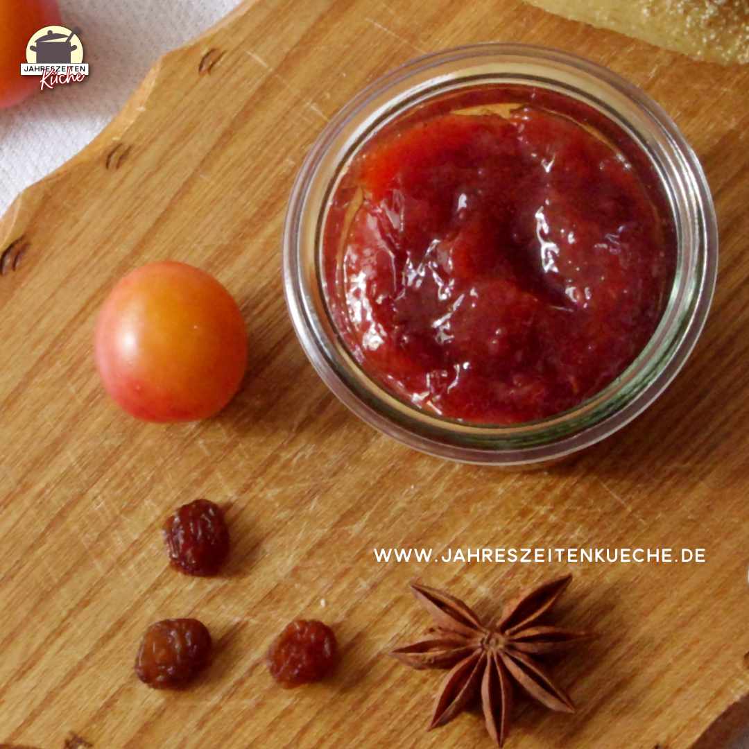Neben einem Glas Wildpflaumen-Rosinen-Marmelade liegen eine Wildpflaumen und Sternanis