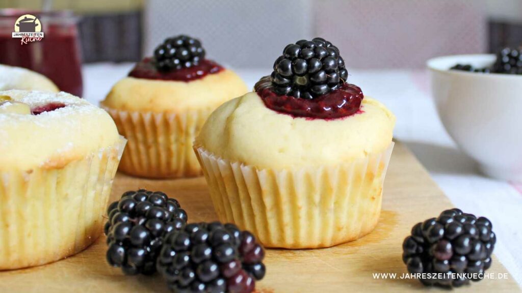 Muffins mit Vanillepudding gefüllt. Darauf liegen Brombeeren.