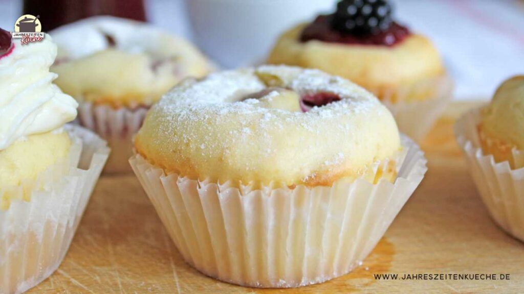 Ein Muffin mit Vanillepudding und Brombeermark gefüllt und mit Puderzucker bestreut