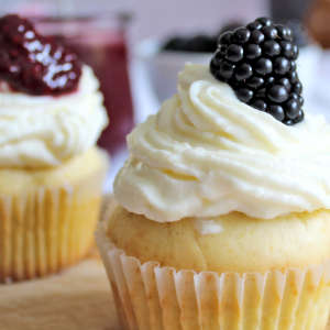Ein Vanillepudding-Muffins mit Frosting und Brombeere garniert.