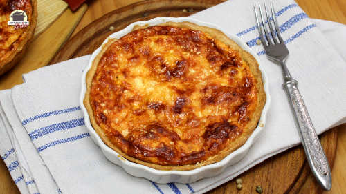 Pastinaken-Quiche in einer weißen Single-Quiche-Form steht auf einem grau-blauen Untersetzer.