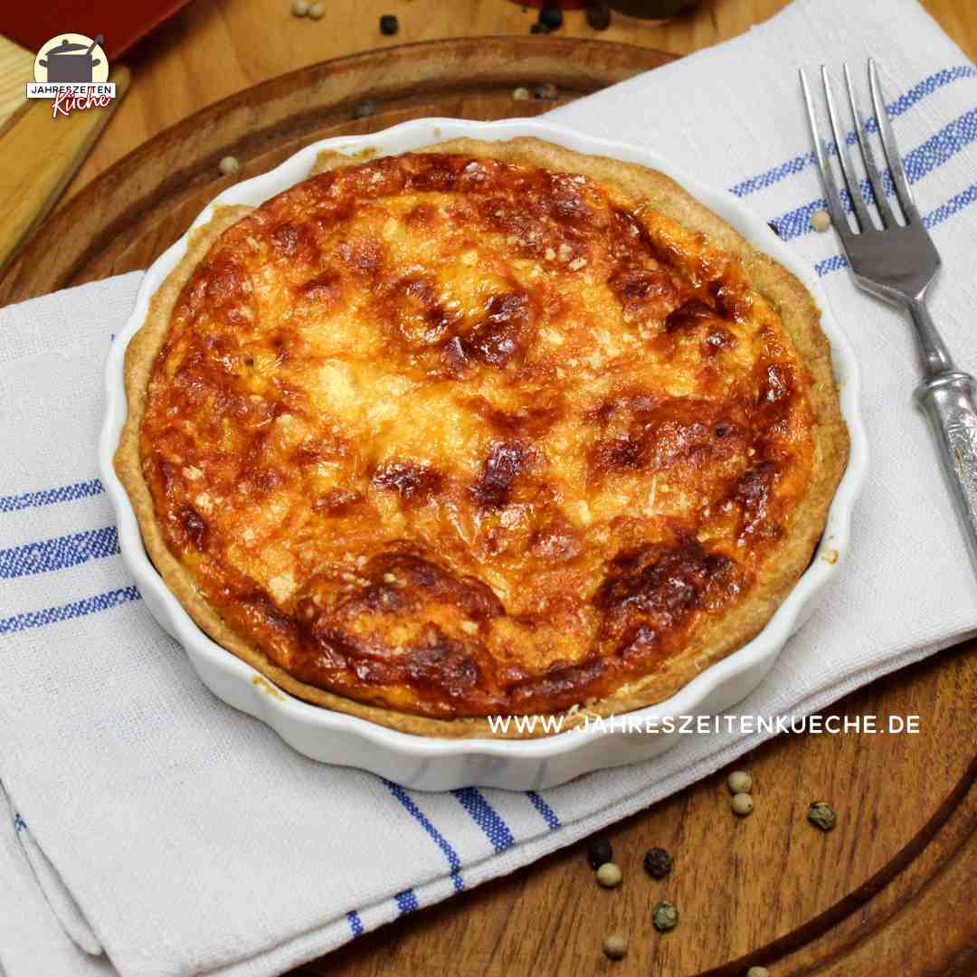 Pastinaken-Quiche in einer kleinen Quiche-Form steht auf einer grau-blauen Leinenserviette.