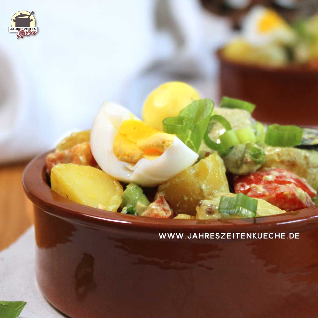 Pellkartoffelsalat mit Lauchzwiebeln bestreut in einer Steingutschale.