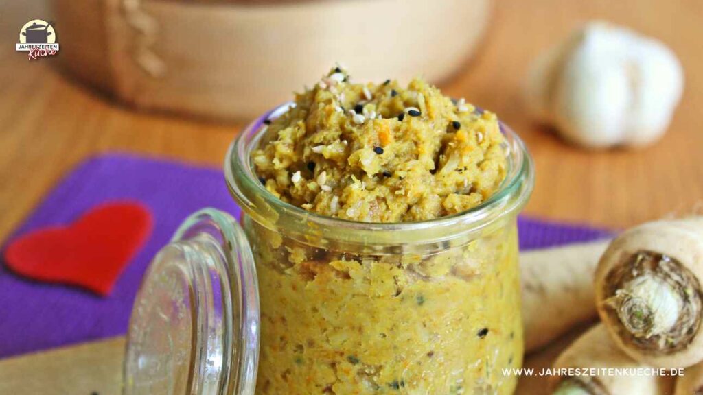 Ein Glas Petersilienwurzel-Aufstrich ist mit Sesam und Schwarzkümmel bestreut.