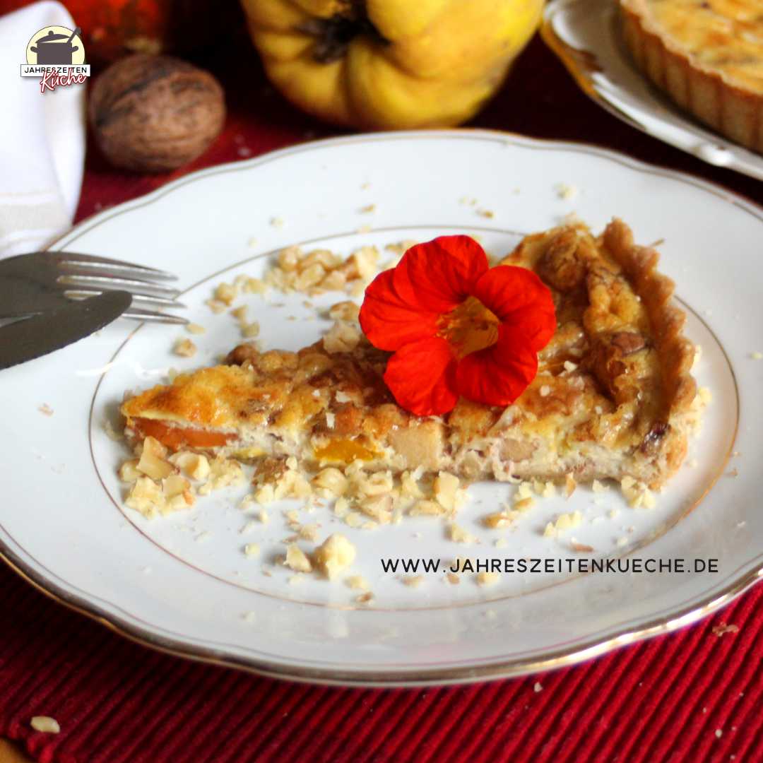 Auf einem Teller mit Goldrand liegt ein Stück Kürbis-Quitten-Quiche mit einer Blüte der Kapuzinerkresse