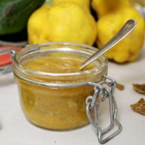 Vor zwei Quitten steht ein Glas Quittenmarmelade.