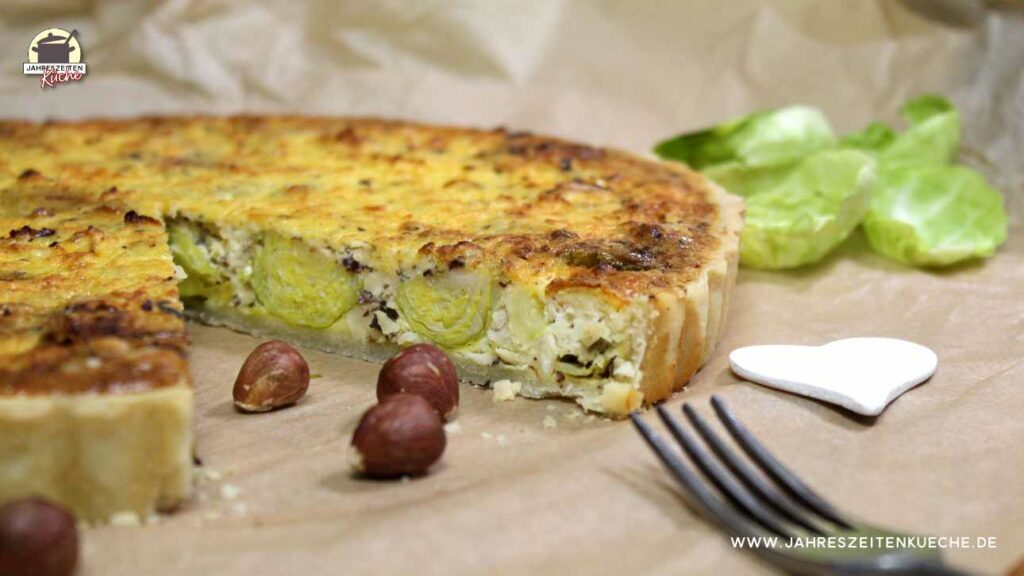 Eine angeschnittene Rosenkohl-Quiche liegt auf einem Stück Backpapier.