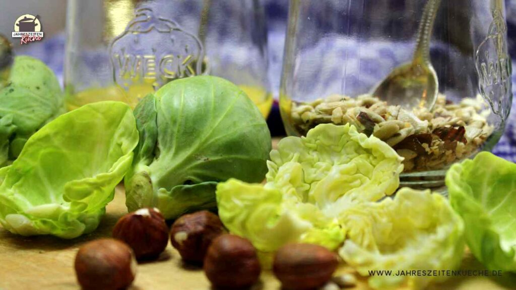 Rosenkohl und Haselnüsse liegen auf einem Holzbrett.