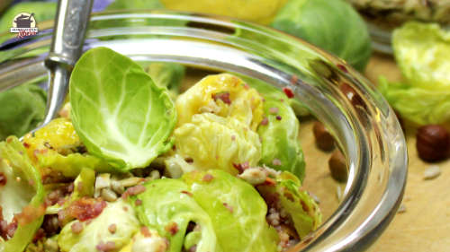 Entblätterte Rosenkohlröschen sind in einer Glasschlüssel mit Bulgur, Haselnüssen und Sonnenblumenkerne angerichtet.