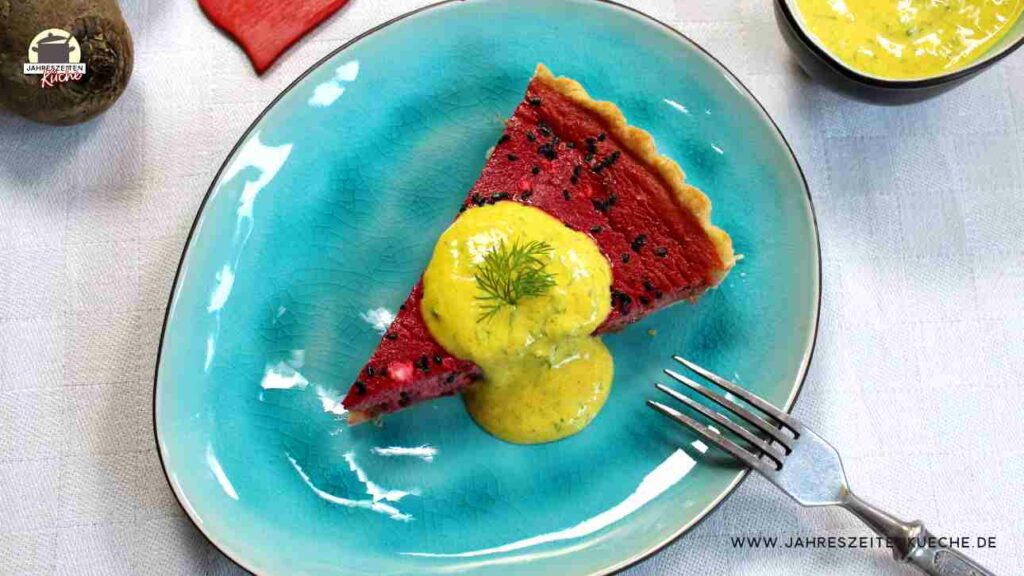 Auf einem ovalen Teller liegt ein Stück Rote-Beete-Quiche. Darauf Joghurtsoße mit Dill.