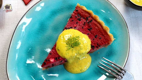 Auf einem ovalen Teller liegt ein Stück Rote-Beete-Quiche. Darauf Joghurtsauce mit Dill.